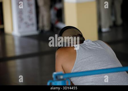 Uomo con le cuffie in attesa nel terminal della barca, presenza umana in ambiente urbano, concetto di vita pubblica, vista posteriore, molo Tha Chang. Foto Stock