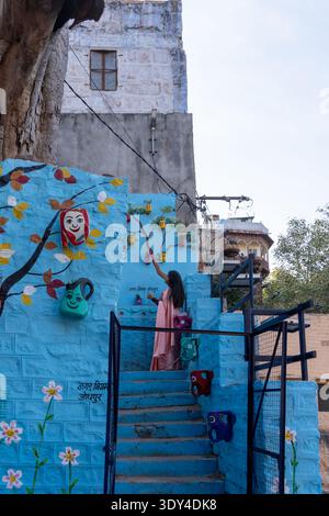 Jodhpur, Rajasthan, India - 30 gennaio 2026: Una giovane donna in piedi sulle scale dipinte di blu nella vecchia città di Jodhpur, Rajasthan, India. Foto Stock