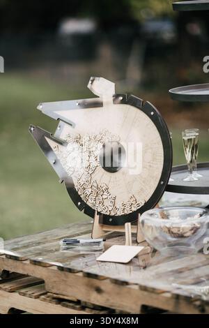 Esposizione di libri per gli ospiti di nozze a tema spaziale dove gli ospiti firmano gettoni di legno e li collocano in una tavola rotante in stile galassia durante il matrimonio all'aperto. Foto Stock