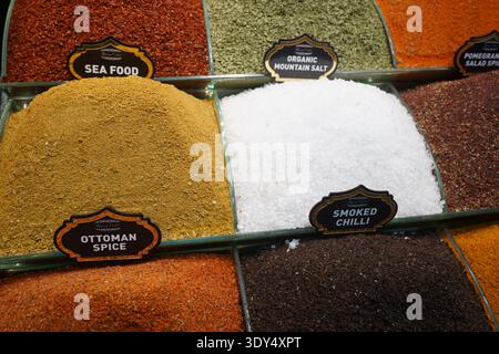 Vivaci cumuli di spezie, erbe e sali turchi aromatici esposti in contenitori di vetro organizzati in un tradizionale mercato delle spezie. Foto Stock