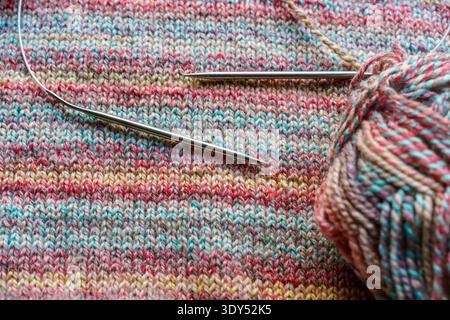 Confortevole scena di lavorazione a maglia fatta a mano con palline colorate in filato di lana e aghi in legno. Foto di alta qualità Foto Stock