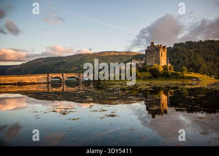 Castello di Eilean Donan al tramonto con Highland Mountain Range e Symmetric Water Reflections, Loch Duich, Scozia, Regno Unito Foto Stock