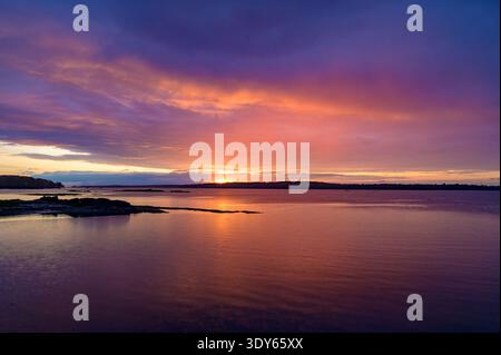 Vivace tramonto sulla costa sulle acque calme Foto Stock