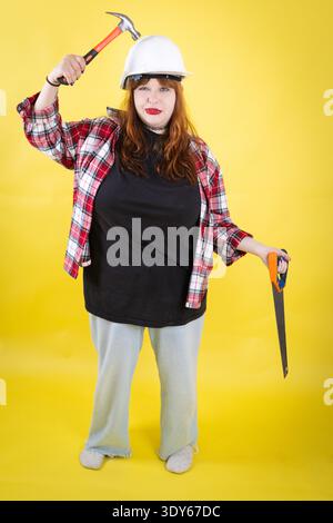 Donna che indossa un elmetto con martello e sega Foto Stock