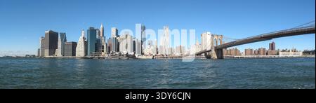 Lo skyline di Manhattan si vede dall'altra parte del fiume con l'One World Trade Center che sorge in primo piano nel centro. Il ponte di Brooklyn si estende sul lato destro. Foto Stock