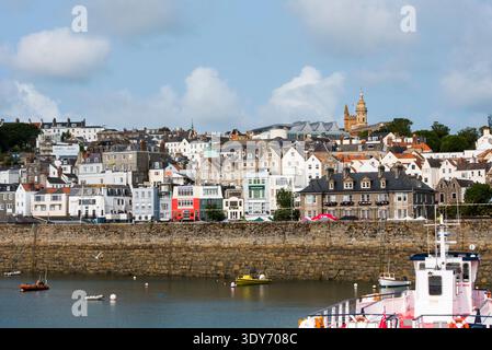 Il porto di St Peter mostra edifici e barche in una giornata di sole sull'isola di Guernsey con un cielo azzurro Foto Stock