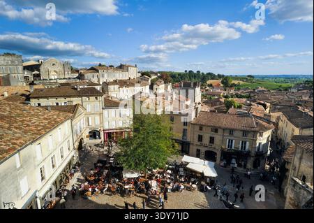 I visitatori apprezzano la piazza di Eglise Monolithe a Saint-Emilion, mentre le bancarelle del mercato riempiono la zona durante una giornata di sole nel sud-ovest della Francia Foto Stock