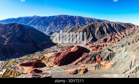 Vista panoramica delle montagne colorate vicino a Purmamarca con cieli illuminati dal sole e valle sottostante Foto Stock