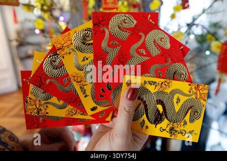 La donna asiatica tiene buste rosse per la celebrazione del capodanno cinese e vietnamita nel 2023, segnando l'anno del serpente in Francia Foto Stock