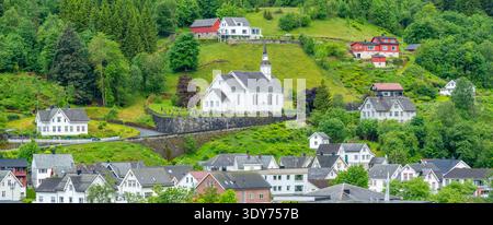 Vista della chiesa Sunnylven e delle case a Hellesylt, circondate dalle verdi colline norvegesi Foto Stock