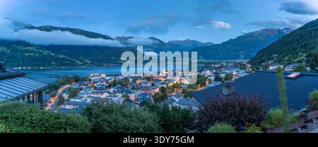 Vista di Zell am SEE e del lago Zell al crepuscolo a Salisburgo, Austria, con luci che si riflettono sull'acqua Foto Stock