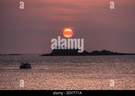 Cielo rosso-dorato al crepuscolo sul Canale della Manica con Fort National e piccole imbarcazioni vicino a Saint Malo Foto Stock