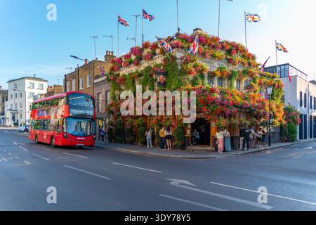 Brillante giornata estiva al Churchill Arms con fiori e visitatori a Kensington Londra Foto Stock
