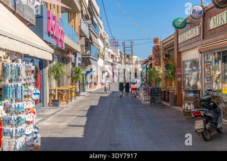 Negozi e caffetterie sulla strada principale di Limenas Chersonisou Creta durante il giorno estivo Foto Stock