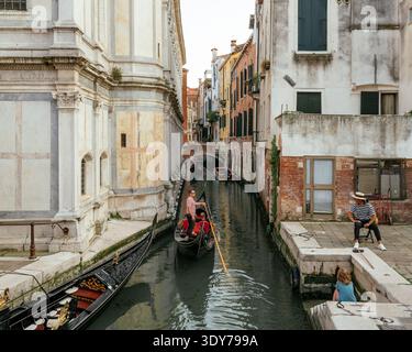 I turisti possono fare un giro in gondola attraverso i canali di Castello a Venezia in una giornata di sole in Veneto Italia Foto Stock