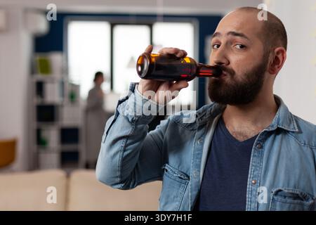 Ritratto di uomo caucasico con bottiglia di birra a dopo il lavoro drink incontro con colleghi. Persona che si diverte con gli amici in ufficio d'affari, godendo festa con cibo e alcol. Foto Stock