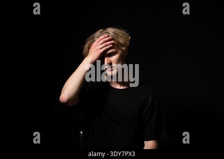Giovane che soffre di dolore e stress, soffre di mal di testa o emicrania grave, si sente frustrato e sopraffatto, ha bisogno di sollievo e riposo Foto Stock