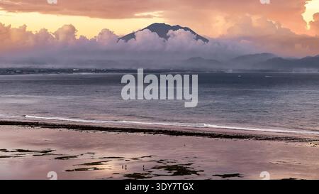 Splendida vista al tramonto della spiaggia di Sanur e del vulcano del monte Agung che si innalza sopra le nuvole di Bali Foto Stock