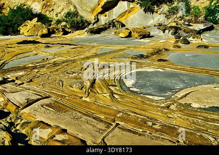 Formazioni geologiche uniche di arenaria intemprata e piscine di marea su una costa rocciosa. Schemi intricati scolpiti dall'erosione e dalle maree Foto Stock