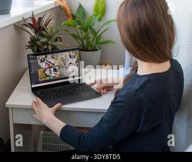 Una donna guarda le riprese delle telecamere a circuito chiuso sul suo computer portatile Foto Stock