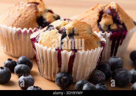 Primo piano: Muffin ai mirtilli fatti in casa con il succo di mirtillo che gocciola nei contenitori di carta Foto Stock
