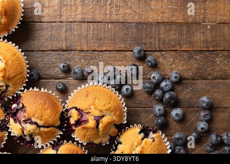 Muffin fatti in casa ai mirtilli e mirtilli freschi su un tavolo in legno rustico scuro con spazio copia Foto Stock