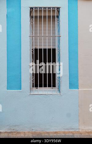 Finestre turchesi con bar su un edificio in mattoni bianchi Foto Stock