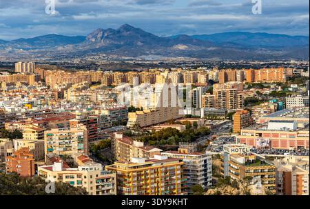 Alicante, Spagna - 20 gennaio 2026: Paesaggio urbano panoramico di Alicante con i quartieri urbani centrali e settentrionali e la catena montuosa della Serra de Mariola Foto Stock