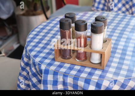 Vasetti di spezie posizionati ordinatamente su un tavolo a scacchi blu e bianco Foto Stock