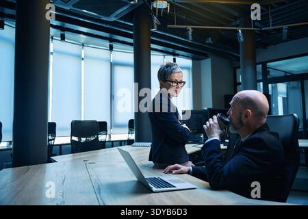 Due adulti che discutono idee con un caffè in un ufficio moderno Foto Stock