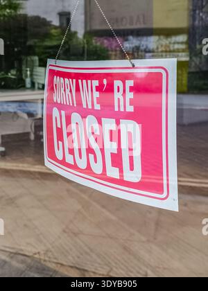 Siamo spiacenti, il cartello è chiuso e viene appeso alla porta della finestra d'ingresso di Un negozio di vetro Foto Stock