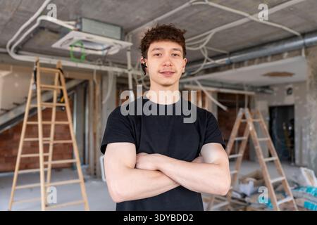 Giovane tecnico hvac in piedi con le braccia incrociate nel cantiere Foto Stock