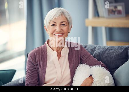Felice, divano e ritratto di una donna anziana per riposare, rilassarsi e riposare nella casa di cura. Pensionamento, sorriso e anziano sul divano per me tempo Foto Stock