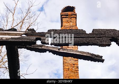Resti di legno carbonizzato e camino in mattoni in piedi dopo il disastro dell'incendio della casa Foto Stock