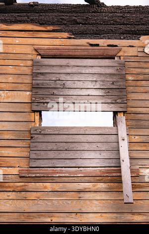 Vecchia facciata in legno con una finestra a bordo e tetto carbonizzato dopo un incendio Foto Stock