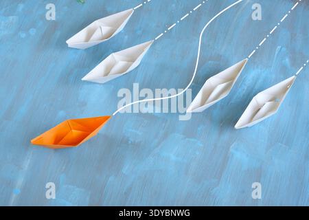 Red Paper Boat seguito da White Paper Boats. Concetto di business per la direzione Foto Stock
