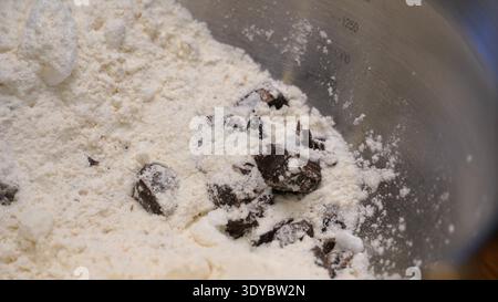 Pezzi di cioccolato e farina nel recipiente per la preparazione dei biscotti Foto Stock