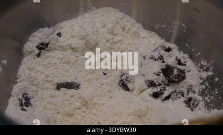 Pezzi di cioccolato e farina nel recipiente per la preparazione dei biscotti Foto Stock