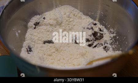 Pezzi di cioccolato e farina nel recipiente per la preparazione dei biscotti Foto Stock