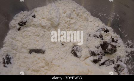 Pezzi di cioccolato e farina nel recipiente per la preparazione dei biscotti Foto Stock