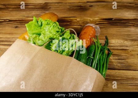 Sacchetto di carta con cibo diverso su un tavolo di legno. Concetto di acquisto di generi alimentari Foto Stock