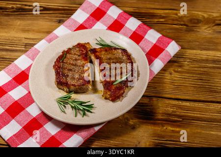 Bistecche di maiale grigliate con rosmarino su un tavolo di legno Foto Stock