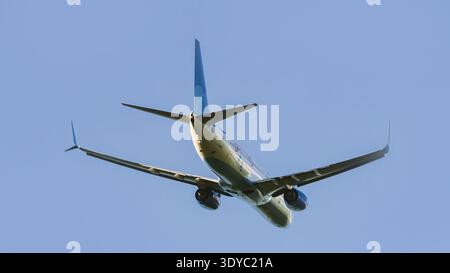 Aereo passeggeri commerciale in decollo, che sale in un cielo blu limpido. Vista ad angolo basso dal basso. Foto Stock