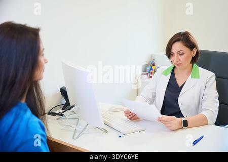 Donna caucasica che si consulta con un'altra donna nello studio medico Foto Stock