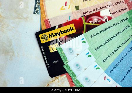 KIEV, UCRAINA - 28 GENNAIO 2026 carta Maybank e banconote del ringgit malese sul tavolo da vicino. Maybank è la banca più popolare in Malesia Foto Stock