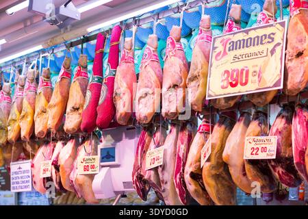 File di tradizionali prosciutti spagnoli Jamón Serrano e Ibérico appesi a un mercato di Madrid, Spagna. Foto Stock
