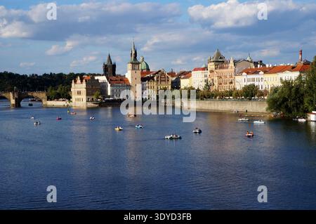 Questa foto finale di Praga è una bellissima composizione illuminata dal sole. Cattura la vibrante energia del fiume Moldava con le barche da diporto e la splendida ar Foto Stock