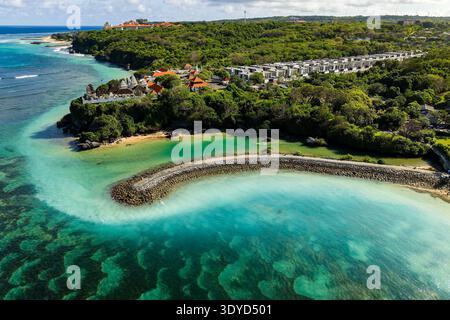 Ripresa in droni della splendida costa di Nusa Dua che mostra la barriera corallina, le ville del resort e gli alberi lussureggianti Foto Stock