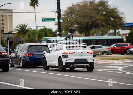 Veicolo elettrico a guida autonoma con array di sensori visibili che si muove tra il traffico cittadino in un incrocio americano, mostrando il trasporto automatizzato e l'innovazione Foto Stock