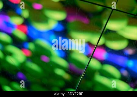 Immagini astratte brillanti che mostrano riflessi di luce colorati su una superficie in vetro graffiato con sfumature verde blu rosa e viola che creano una colorazione dinamica Foto Stock